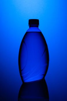 Transparent blue plastic bottle on the blue background.