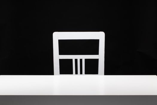 White old chair and the wooden white table in the dark room.