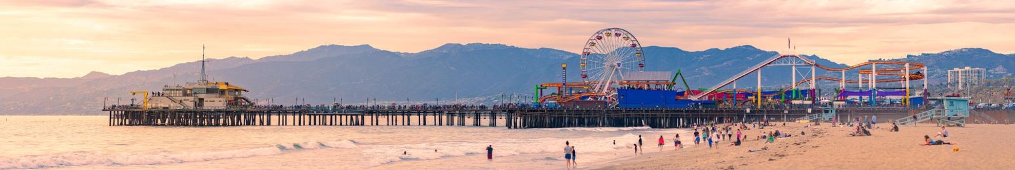 Santa Monica, United States of America - October 24, 2016: panorama of Pacific Park with pier, Ferris wheel, beach, ocean and mountains at sunset.