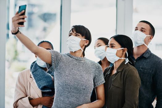 Shot of a group of young people wearing masks and taking selfies at the airport