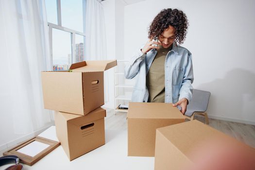 handsome guy with a phone in hand with boxes moving interior. High quality photo