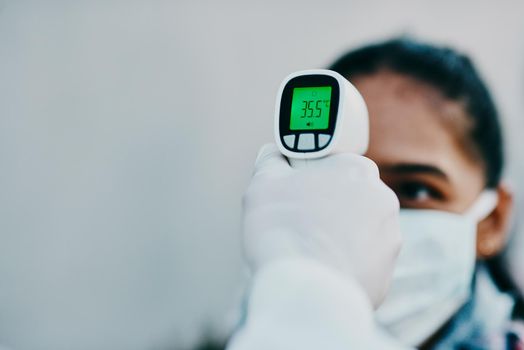 Shot of a young woman getting her temperature taken with an infrared thermometer by a healthcare worker during an outbreak