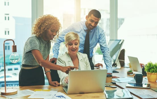 Shot of a group of businesspeople working together on a laptop in an office