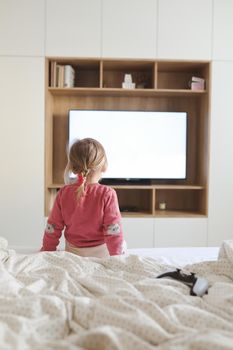 Little cute girl watching television at home.