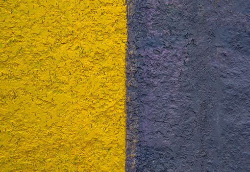 The surface is painted in half in yellow and black. Paint on a concrete wall. Texture of a colored surface. Black and yellow color. background image. Template for text. Two vertical halves.