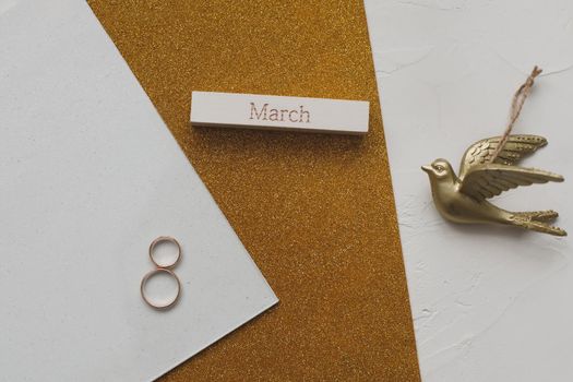 8 March, International Women's Day background with decor elements. Eight made of two gold wedding rings and word MARCH. Greeting card for March 8. Flat lay, top view, copy space