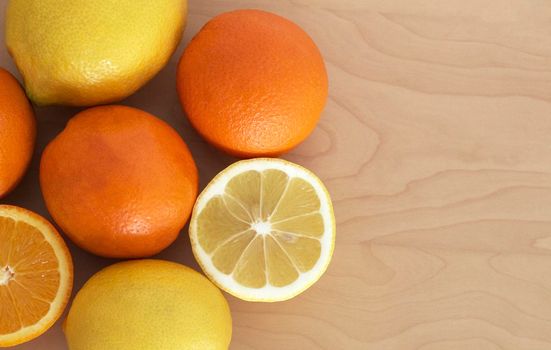 fresh citrus lemons and oranges are grouped on a wooden table. some of them are cut and its juice is visible. perfect aroma and vitamins. its color is a great antidepressant