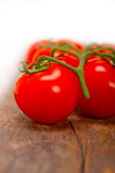 fresh cherry tomatoes on a cluster over rustic wood table