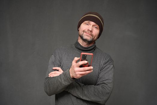 Portrait of a man with a phone and a smile on a gray background