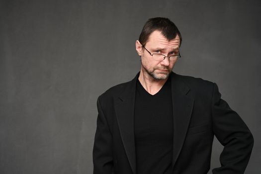 Portrait of an adult man in glasses with disbelief on a gray background