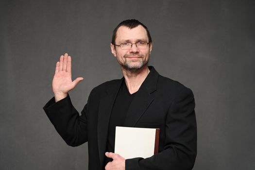 Portrait of an adult male accountant in glasses with a smile and a folder in his hands on a gray background