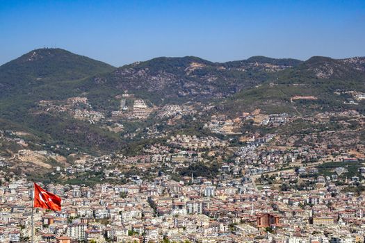 The waving flag of Turkey. Against the background of the city of Alanya and the mountains.