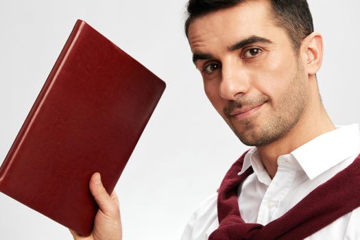 successful man in a white shirt sweater on the shoulders notebook posing light background. High quality photo