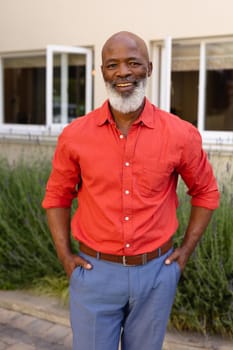 Portrait of african american senior man with hands in pockets smiling while standing outdoors. people and emotions concept, unaltered.