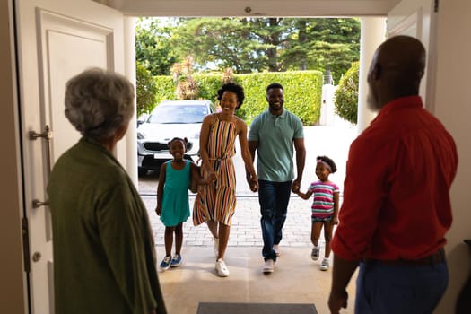 African american senior couple welcoming their family while standing on the front door at home. family, love and togetherness concept, unaltered.