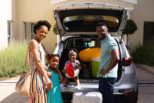 Portrait of african american family smiling while standing near their car. family trip and vacation concept, unaltered.