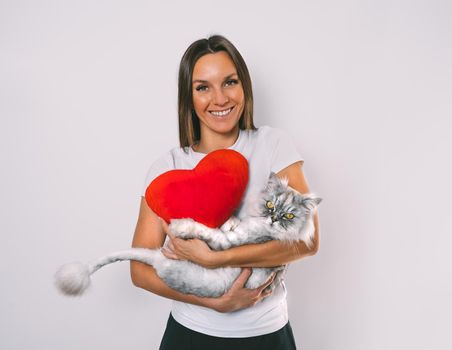 Woman with red heart toy holding her lovely cat in arms. Love for pets. Valentine's day concept. Copy space. High quality photo