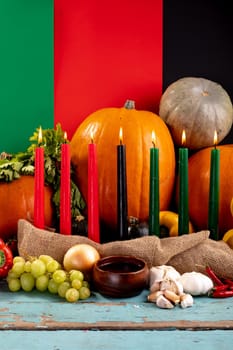 Composition of halloween decoration with candles and pumpkins on tricoloured background. horror, fright, halloween tradition and celebration concept digitally generated image.