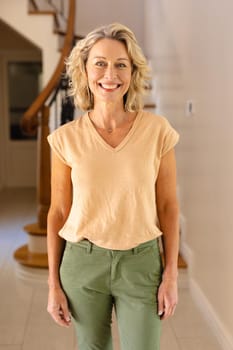 Portrait of caucasian senior woman smiling while standing in the living room at home. people and emotions concept, unaltered.