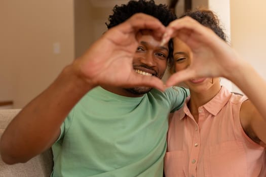 Biracial couple making heart shape with hands gesturing love at valentine's day. love and lifestyle unaltered.