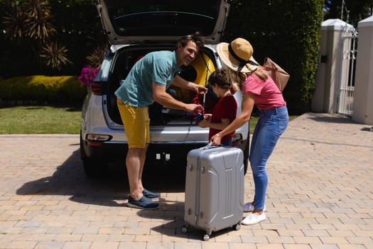 Happy caucasian family putting their luggage in car on sunny day. family trip and vacation concept, unaltered.