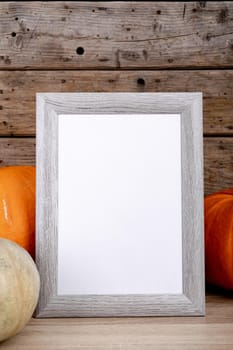 Composition of halloween decoration with pumpkins and frame with copy space on wooden background. halloween tradition and celebration concept digitally generated image.