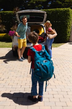 Happy caucasian family putting all their luggage in their car on sunny day. family trip and vacation concept, unaltered.