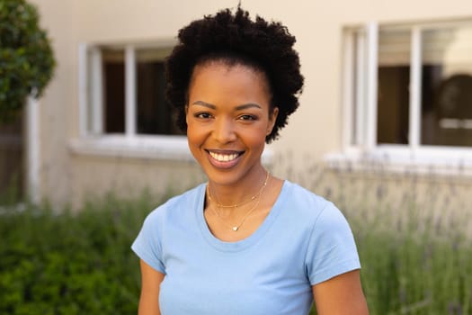 Close-up portrait of smiling african american young woman smiling while standing outdoors. people and emotions concept, unaltered.