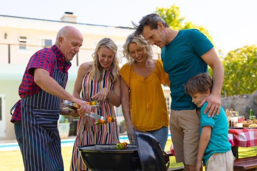 Three generational caucasian family barbecuing together in the garden. family, togetherness and weekend lifestyle concept, unaltered.