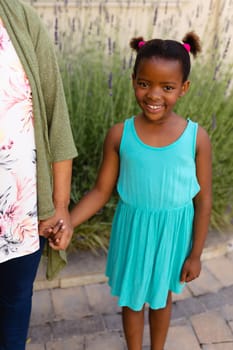 Portrait of african american girl holding hands of her granddaughters while standing outdoors. family, love and togetherness concept, unaltered.