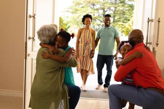African american girls hugging their grandparents on the front door at home. family, love and togetherness concept, unaltered.