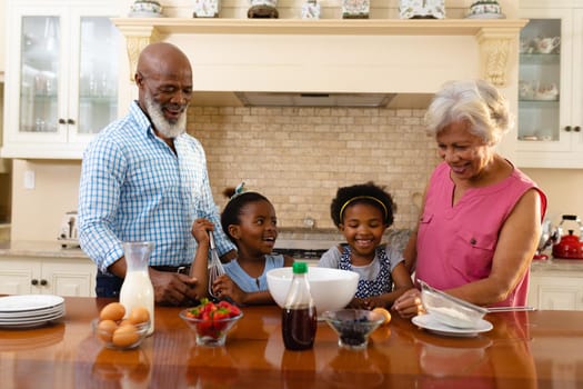 African american grandparents and granddaughters baking together in the kitchen at home. family, love and togetherness concept, unaltered.
