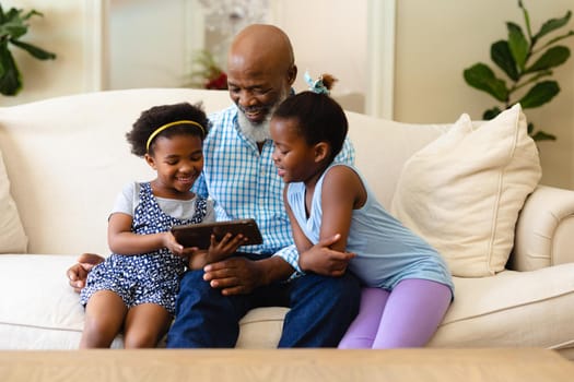 African american grandfather and his two granddaughters using digital tablet at home. family, love and technology concept, unaltered.