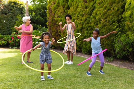 Playful african american family enjoying with plastic hoops at backyard garden. family, love and togetherness concept, unaltered.