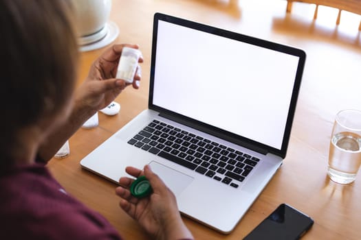 Senior woman with medicine using laptop during online doctor consultation at home, copy space. lifestyle, wireless technology, telemedicine and healthcare.