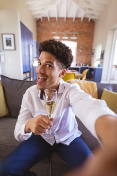 Portrait of cheerful young man holding champagne flute during virtual date at home. lifestyle and virtuality.