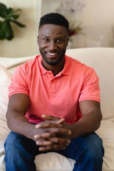 Portrait of african american man smiling while sitting on the couch at home. people and emotions concept, unaltered.