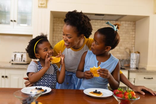 African american mother and her two daughters having breakfast in the kitchen at home. family, love and togetherness concept, unaltered.