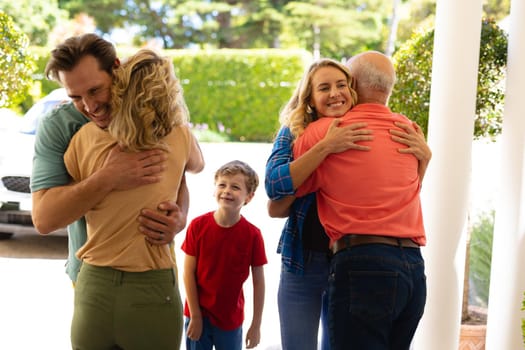 Rear view of caucasian senior couple hugging their family at the entrance of house. family, love and togetherness concept, unaltered.