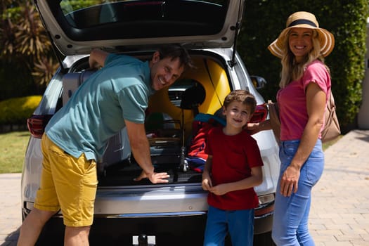 Portrait of caucasian family putting their luggage in their car on sunny day. family trip and vacation concept, unaltered.