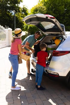 Happy caucasian family loading their luggage in their car outdoors. family trip and vacation concept, unaltered.