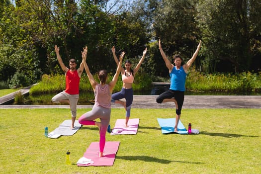 Female instructor teaching yoga to men and woman in park. healthy lifestyle and body care.