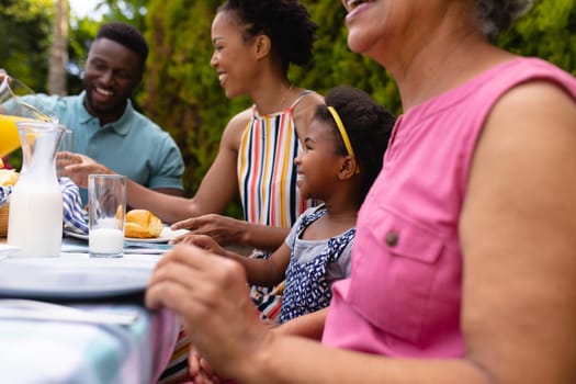 Smiling african american family enjoying brunch at backyard garden. family, love and togetherness concept, unaltered.