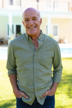 Portrait of caucasian senior man smiling while standing in the backyard garden. people and emotions concept, unaltered.