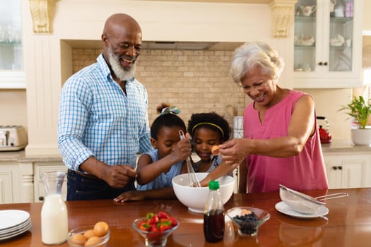 African american grandparents and two granddaughters baking together in kitchen at home. family, love and togetherness concept, unaltered.
