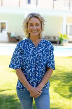 Portrait of caucasian senior woman smiling while standing in garden. people and emotions concept, unaltered.