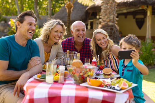 Happy caucasian three generational family taking a selfie with smartphone in the garden. family, togetherness and weekend lifestyle concept, unaltered.