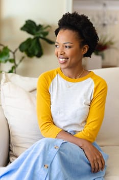 African american young woman smiling sitting on the couch at home. people and emotion concept, unaltered.