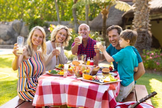 Portrait of happy three generational family toasting drinks at table in the garden. family, togetherness and weekend lifestyle concept, unaltered.