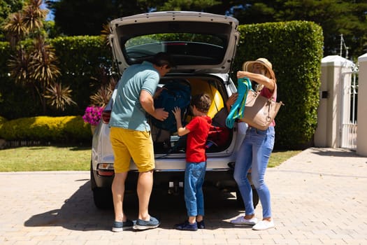 Happy caucasian family putting all their luggage in their car outdoors. family trip and vacation concept, unaltered.